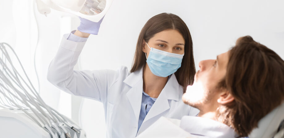 dentist in mask turning on lamp before making check up